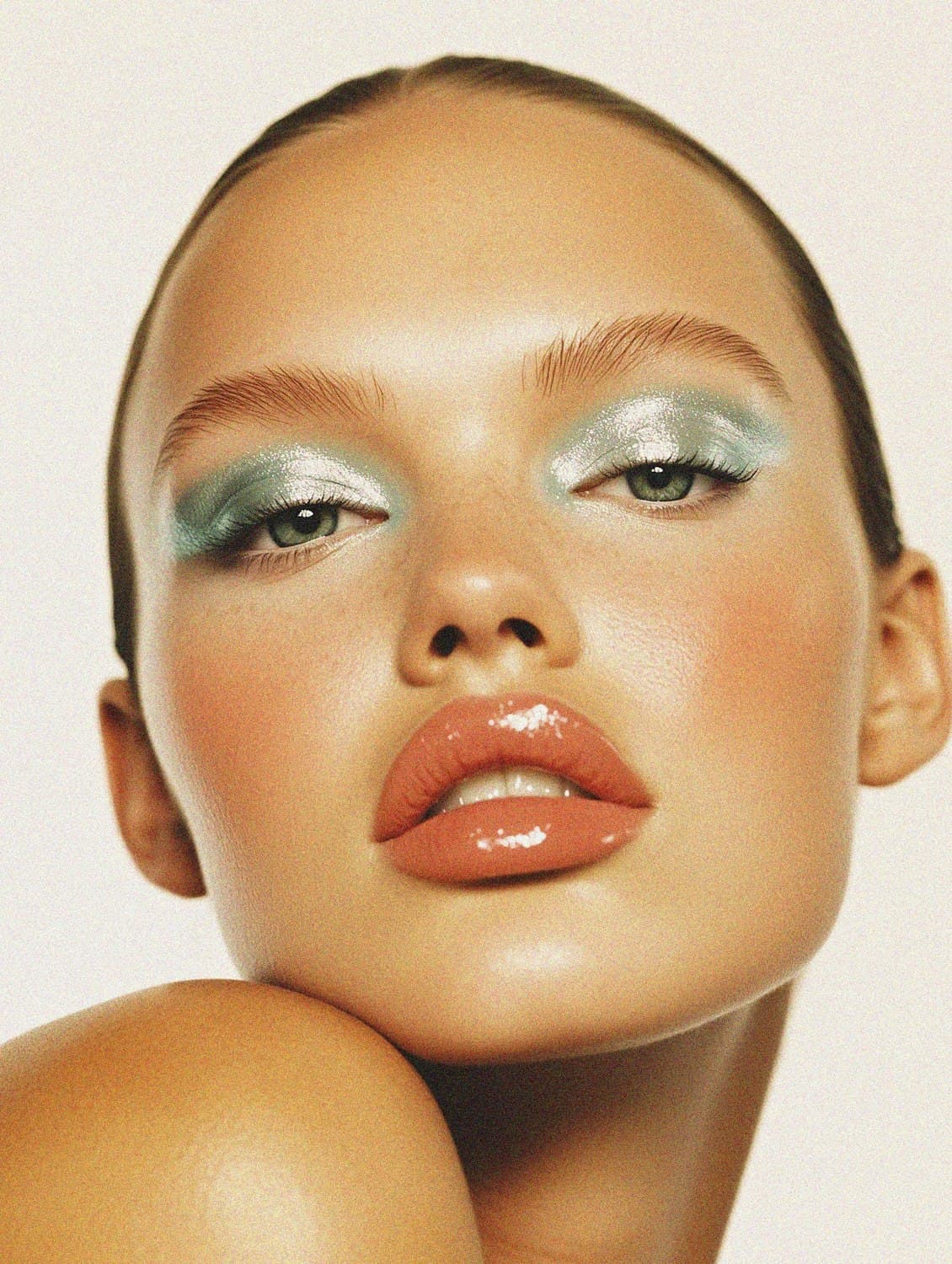 Full glam eye in shimmering blue shadow paired with a glossy peach lip