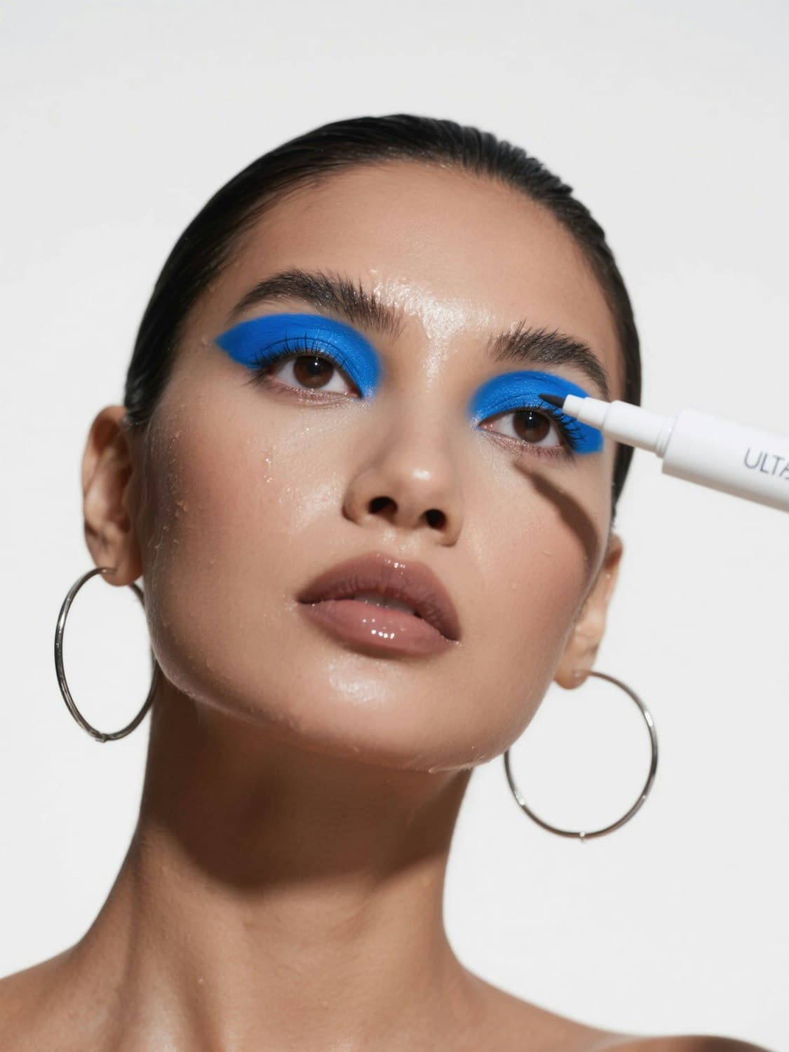 Editorial look with graphic blue shadow, a nude lip and silver hoop earrings